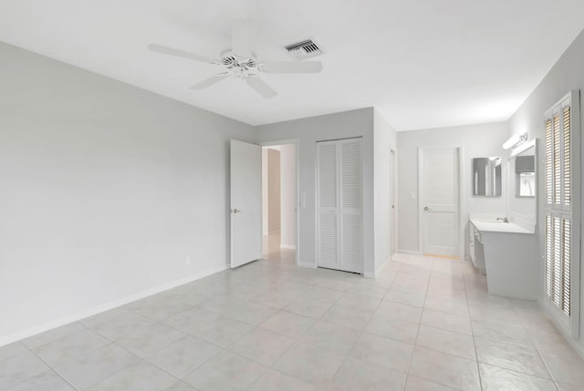 unfurnished bedroom with ceiling fan, light tile patterned floors, sink, and connected bathroom