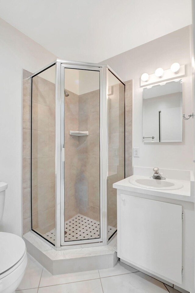 bathroom featuring tile patterned flooring, vanity, toilet, and a shower with door