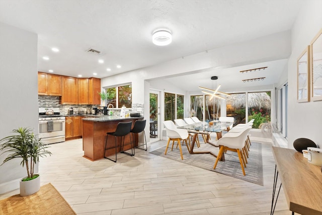 kitchen with sink, a breakfast bar, tasteful backsplash, gas stove, and kitchen peninsula