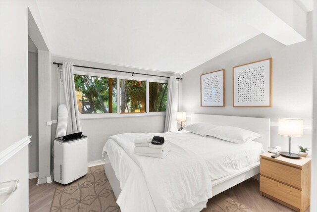 bedroom with lofted ceiling and wood-type flooring