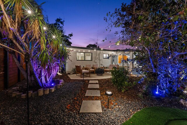 back house at dusk with outdoor lounge area and a patio area