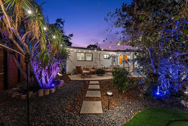 back house at dusk featuring a patio