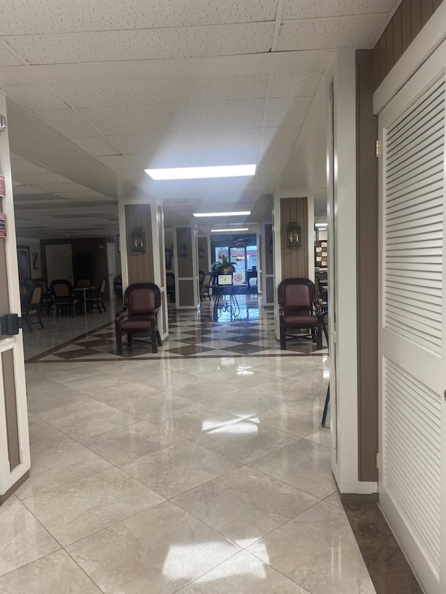 hallway with tile floors and a drop ceiling