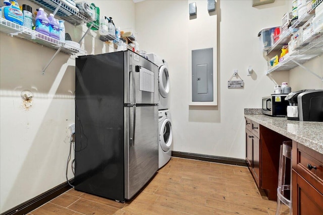 washroom with light wood-type flooring, electric panel, and stacked washer and clothes dryer