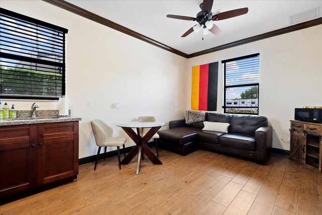 living room featuring ceiling fan, light hardwood / wood-style flooring, ornamental molding, and sink