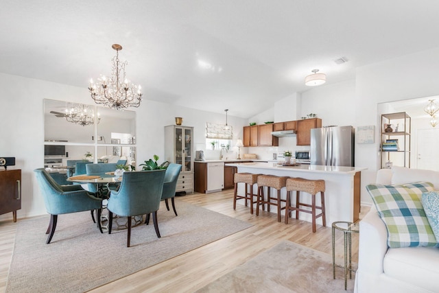 dining space with an inviting chandelier, sink, vaulted ceiling, and light wood-type flooring