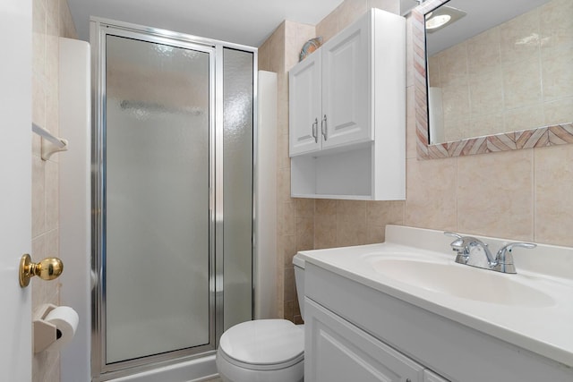 bathroom with vanity, a shower with door, toilet, tile walls, and tasteful backsplash