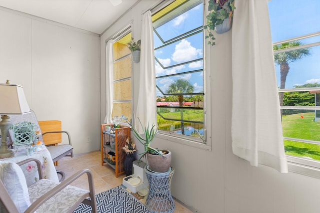 sitting room with a water view, plenty of natural light, and light tile patterned floors