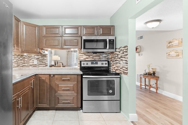 kitchen featuring decorative backsplash, light tile patterned flooring, and stainless steel appliances