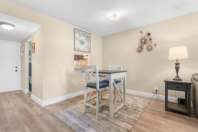 dining area with light wood-type flooring and a textured ceiling