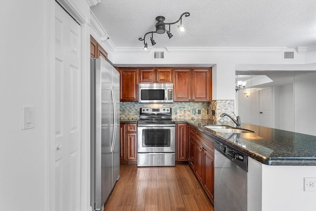 kitchen featuring appliances with stainless steel finishes, a textured ceiling, sink, dark wood-type flooring, and kitchen peninsula