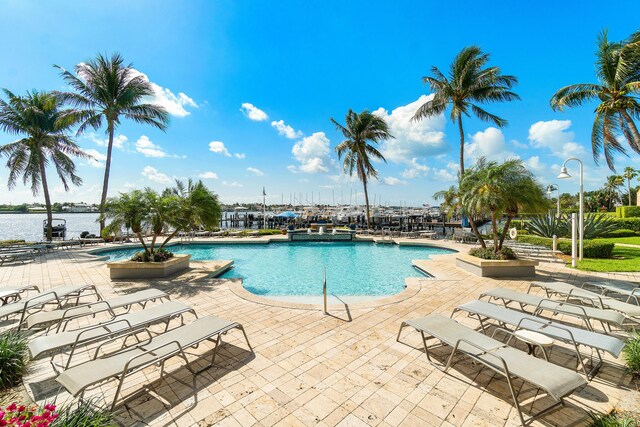 view of pool featuring a water view and a patio