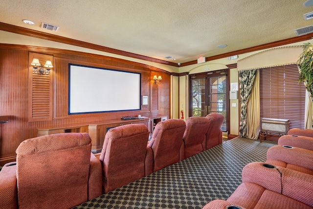 cinema with wooden walls, a textured ceiling, carpet, and ornamental molding