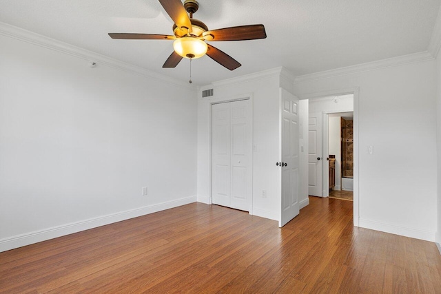 unfurnished bedroom featuring a closet, hardwood / wood-style floors, ceiling fan, and crown molding