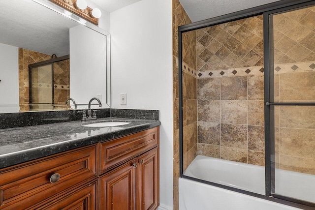 bathroom featuring vanity, bath / shower combo with glass door, and a textured ceiling