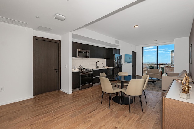 dining area with light hardwood / wood-style floors, a wall of windows, and sink