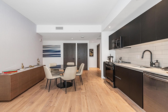 kitchen featuring black appliances, tasteful backsplash, sink, and light hardwood / wood-style flooring