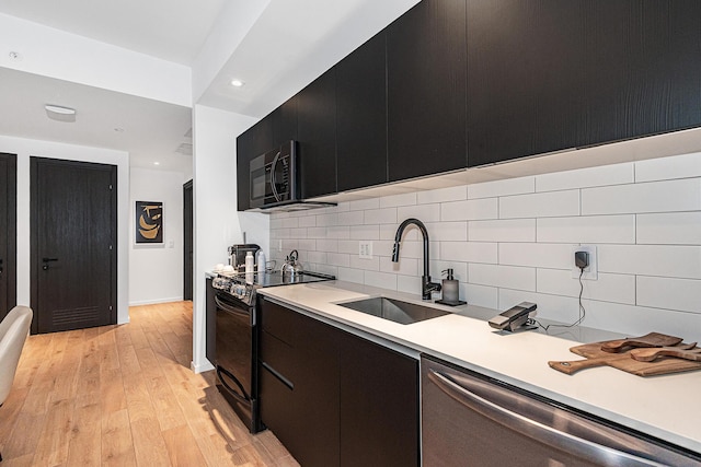 kitchen featuring sink, light wood-type flooring, backsplash, and black appliances