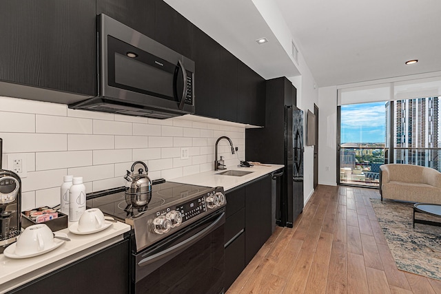 kitchen featuring electric range, tasteful backsplash, light hardwood / wood-style flooring, and sink