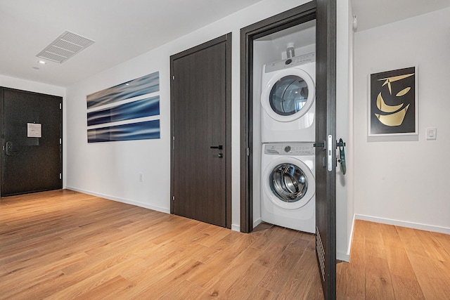 washroom with stacked washer and dryer and light hardwood / wood-style flooring