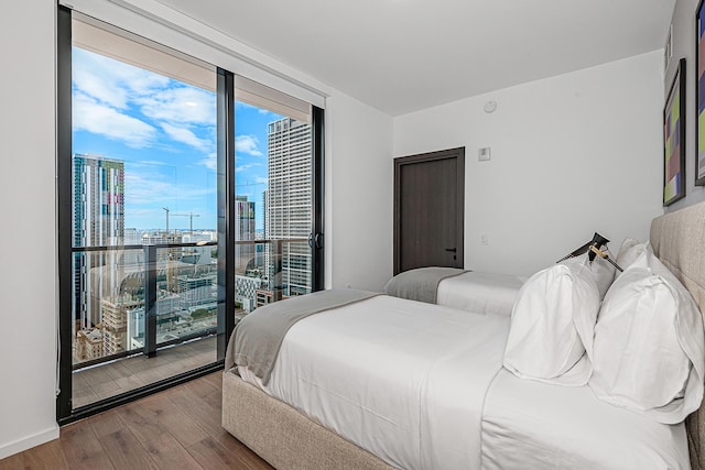 bedroom featuring hardwood / wood-style flooring, floor to ceiling windows, and access to outside