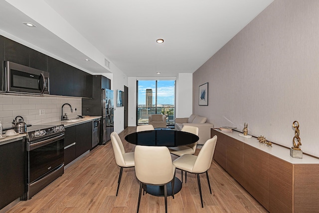 dining room with light hardwood / wood-style floors, a wall of windows, and sink