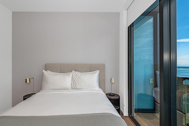 bedroom featuring hardwood / wood-style flooring and a water view