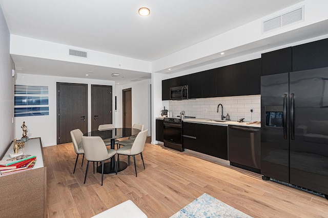 kitchen with black appliances, light hardwood / wood-style floors, sink, and tasteful backsplash