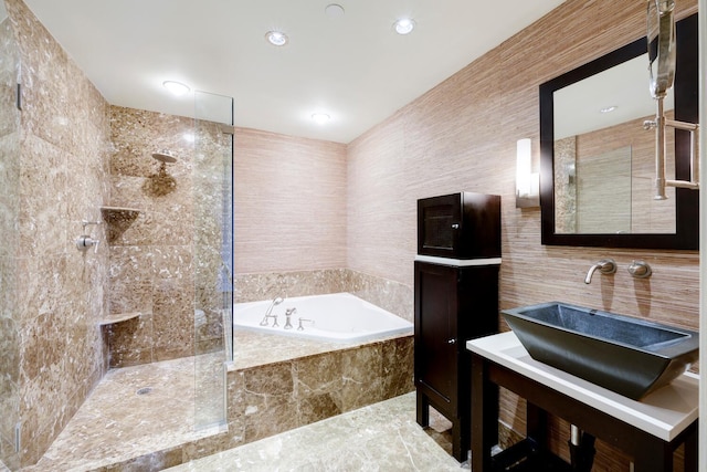 bathroom featuring shower with separate bathtub and tile walls