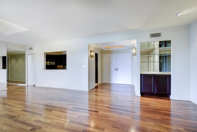 empty room with crown molding and hardwood / wood-style floors