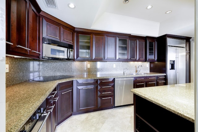 kitchen with appliances with stainless steel finishes, decorative backsplash, light stone counters, and sink