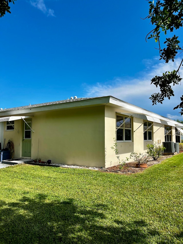 view of side of home featuring central AC and a yard