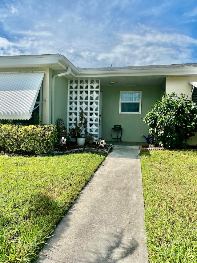 view of exterior entry with a yard