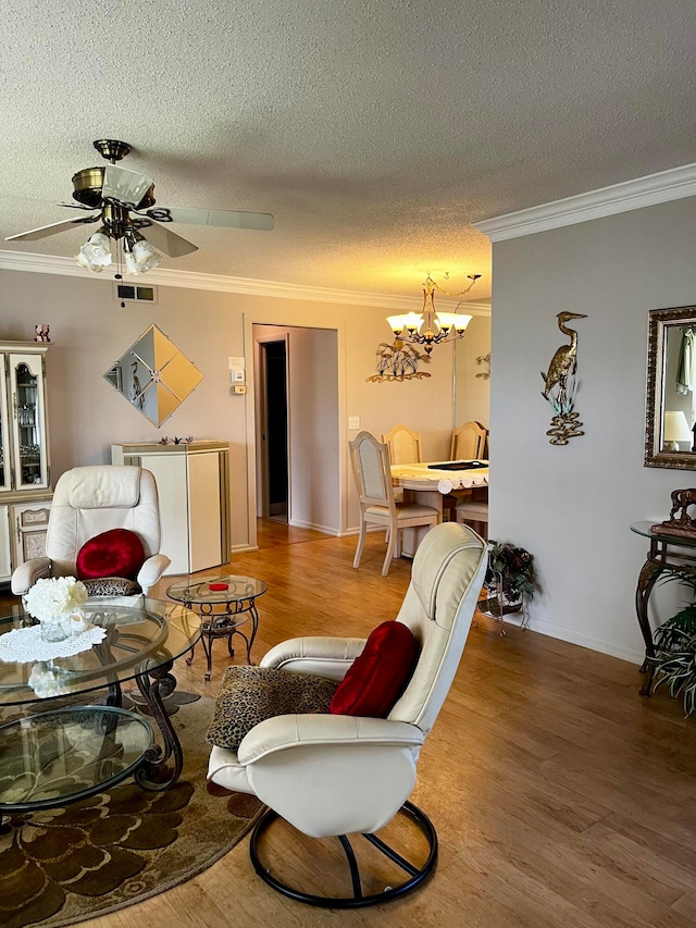 living room with a textured ceiling, wood-type flooring, ceiling fan with notable chandelier, and crown molding