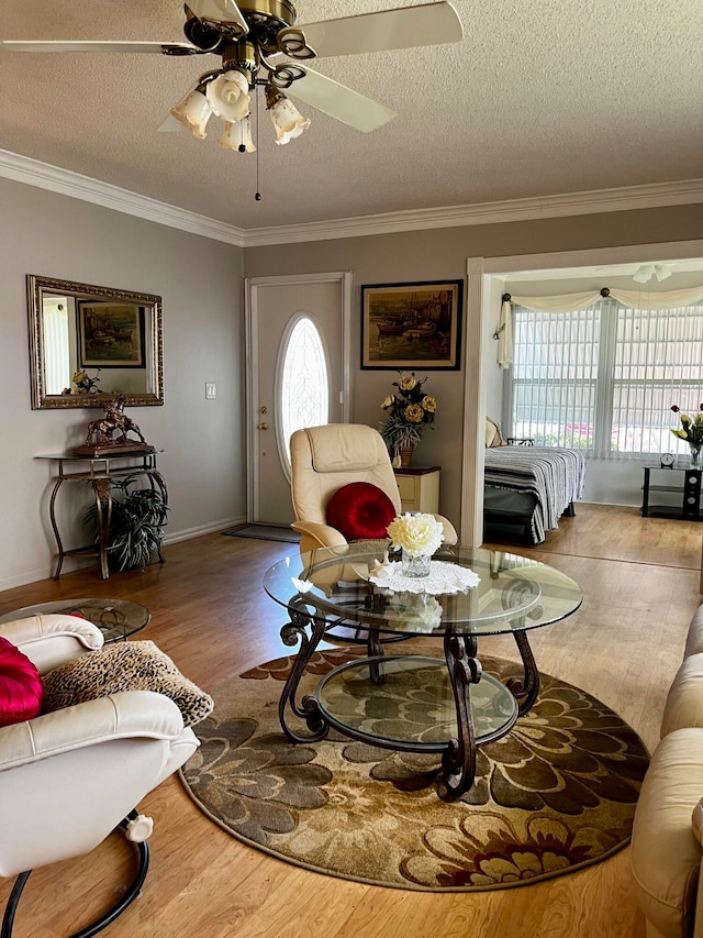 living room featuring crown molding, a textured ceiling, ceiling fan, and light hardwood / wood-style floors