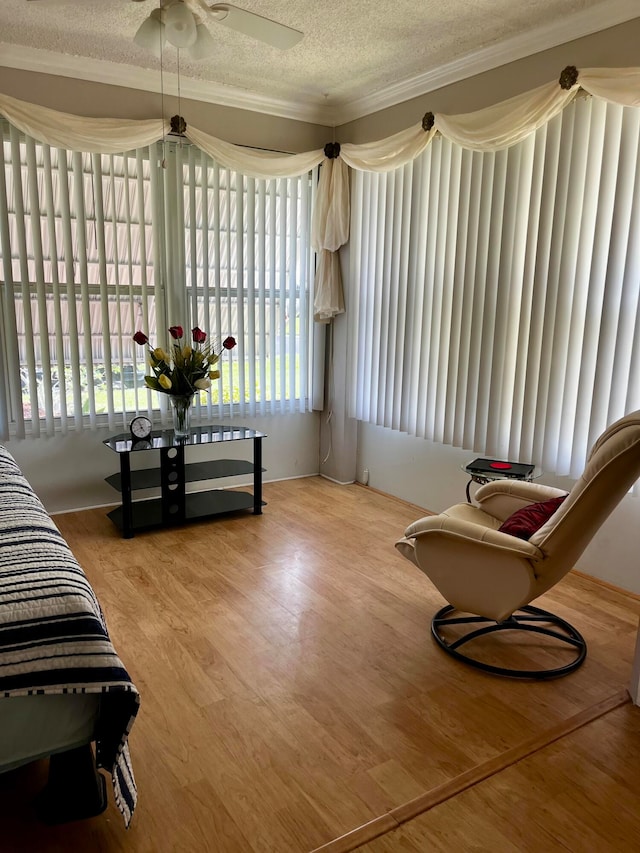 sitting room featuring crown molding, a textured ceiling, wood-type flooring, and a healthy amount of sunlight