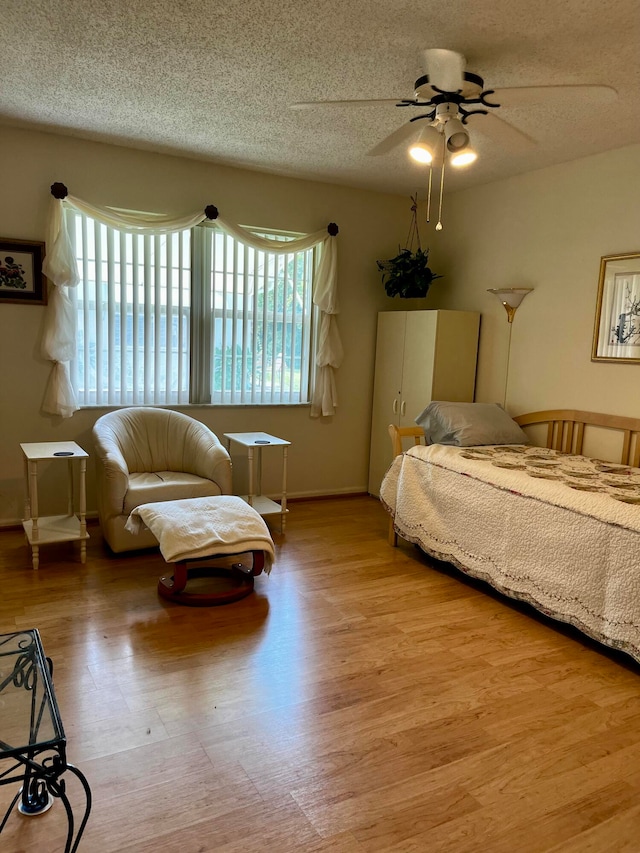 bedroom with light hardwood / wood-style floors, a textured ceiling, and ceiling fan