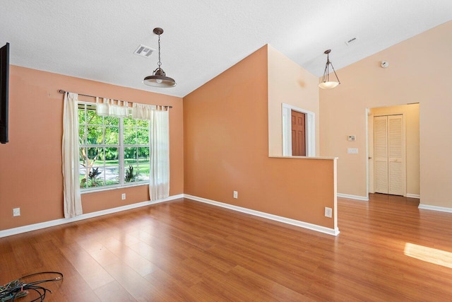 unfurnished room with a textured ceiling, lofted ceiling, and hardwood / wood-style flooring