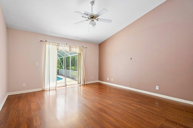 empty room featuring vaulted ceiling, a textured ceiling, ceiling fan, and hardwood / wood-style floors