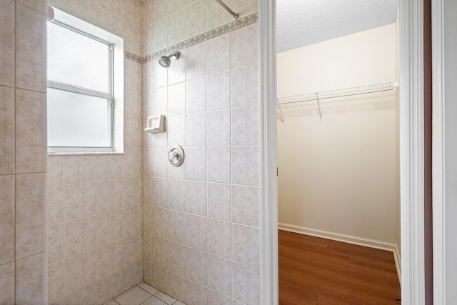 bathroom featuring wood-type flooring, a textured ceiling, and a tile shower