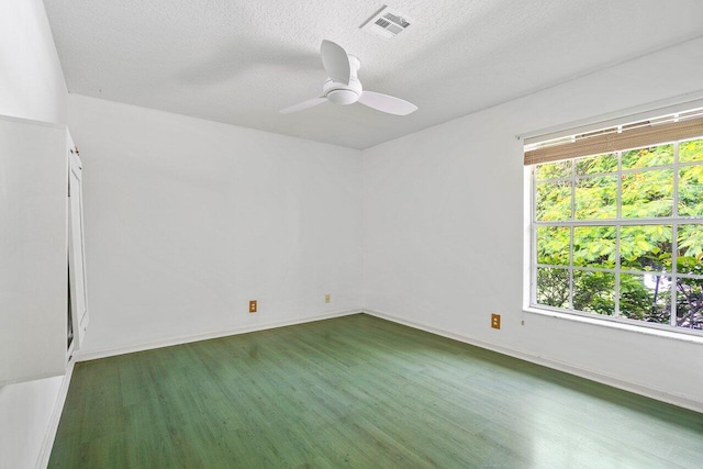 spare room with a wealth of natural light, ceiling fan, and dark hardwood / wood-style floors