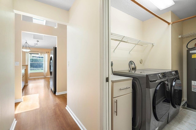 washroom featuring washer and dryer, light hardwood / wood-style flooring, and cabinets