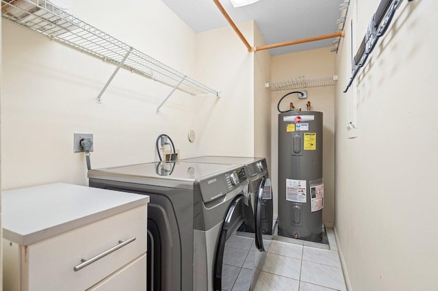 washroom with electric water heater, separate washer and dryer, cabinets, and light tile patterned floors