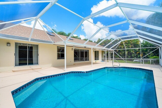 view of swimming pool featuring a patio and glass enclosure