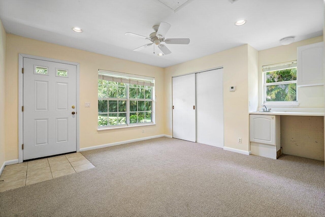 carpeted entryway with ceiling fan and plenty of natural light