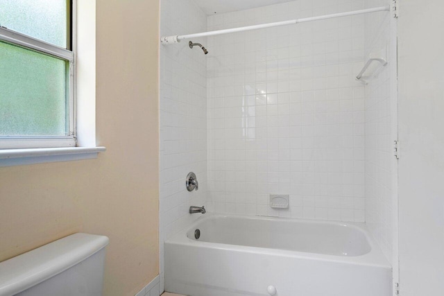 bathroom with tiled shower / bath combo and toilet