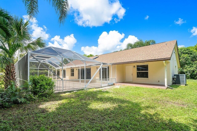 rear view of house with a lanai, a patio area, central AC, and a yard