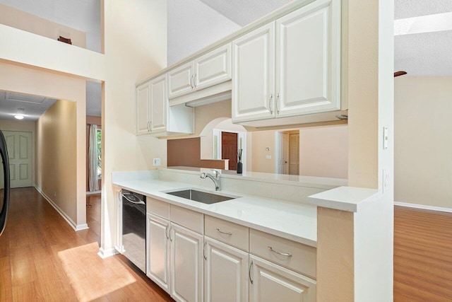 kitchen featuring sink, black dishwasher, a textured ceiling, and light wood-type flooring