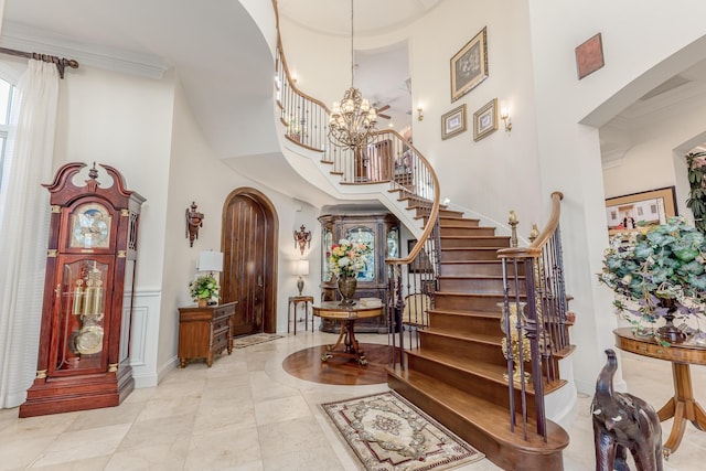 entryway with an inviting chandelier, ornamental molding, and a high ceiling