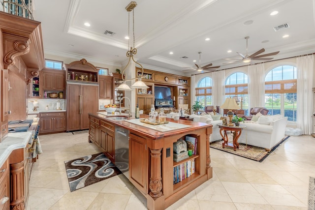 kitchen featuring a spacious island, sink, paneled built in refrigerator, a raised ceiling, and pendant lighting